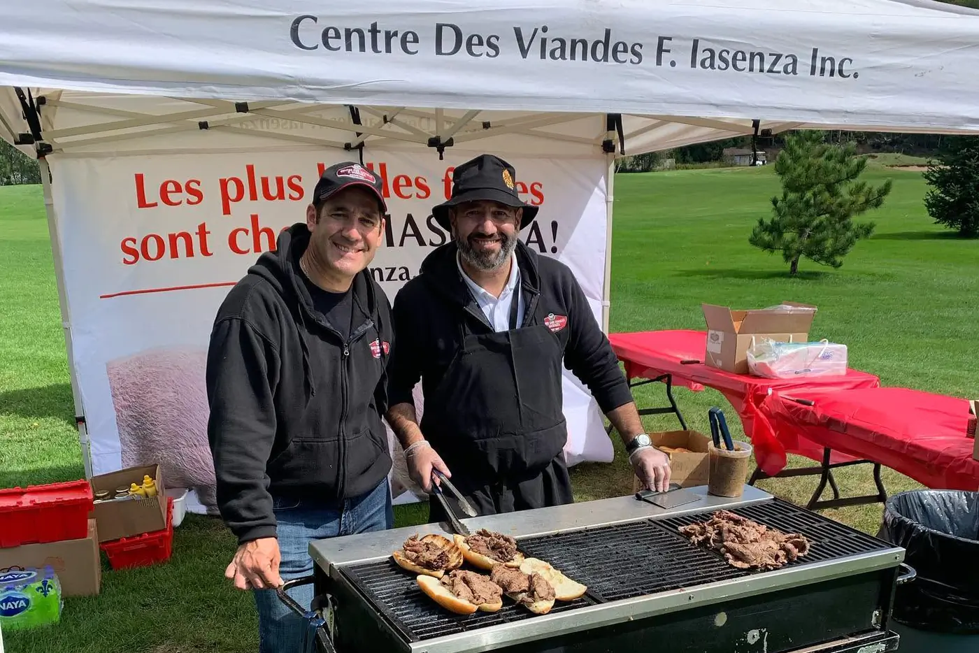 Two Iasenza team members grilling meat sandwiches under a Centre des Viandes F. Iasenza tent at an outdoor event