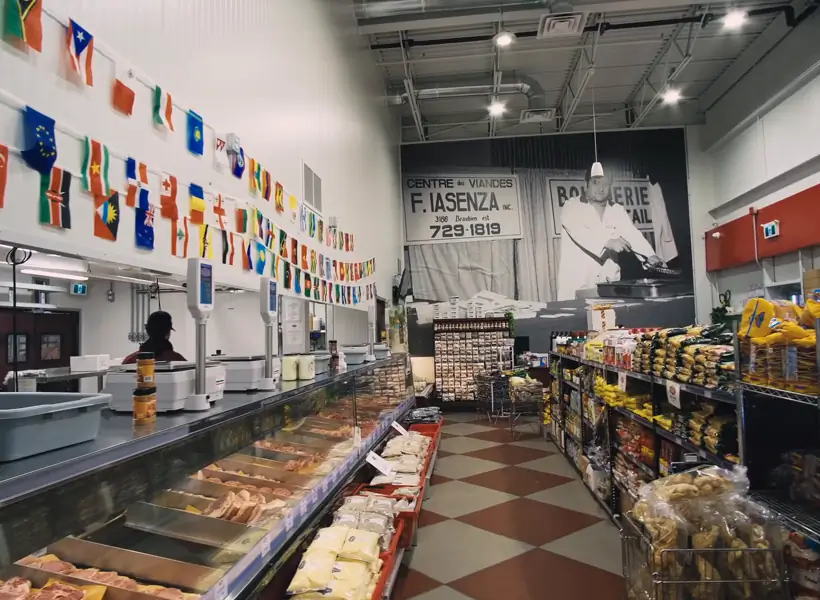 Grocery aisle and refrigerated counters under flags from around the world in an Iasenza store