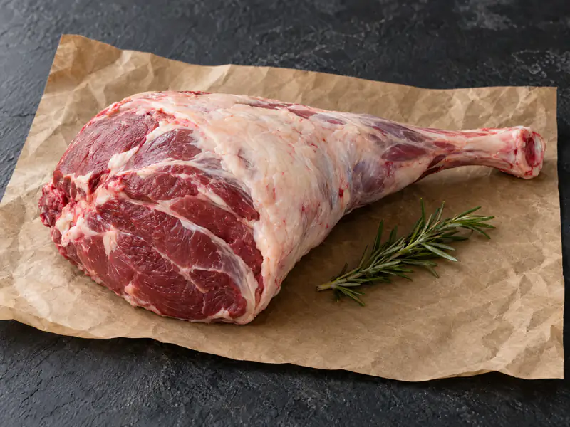 Raw bone-in mutton leg on butcher paper