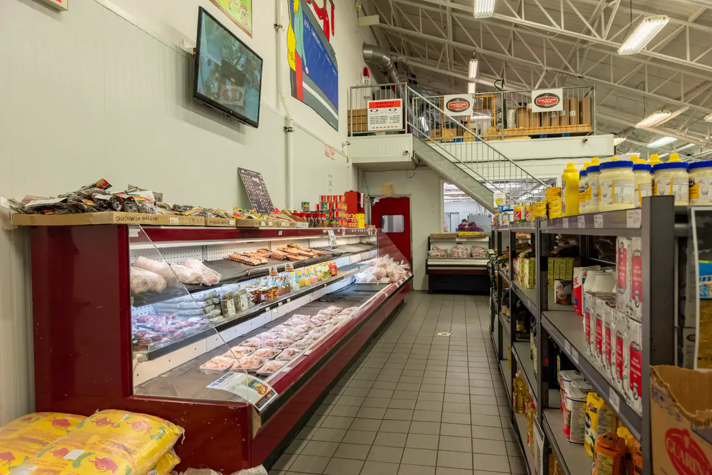 Aisle between a refrigerated case and grocery shelves at the Laval store