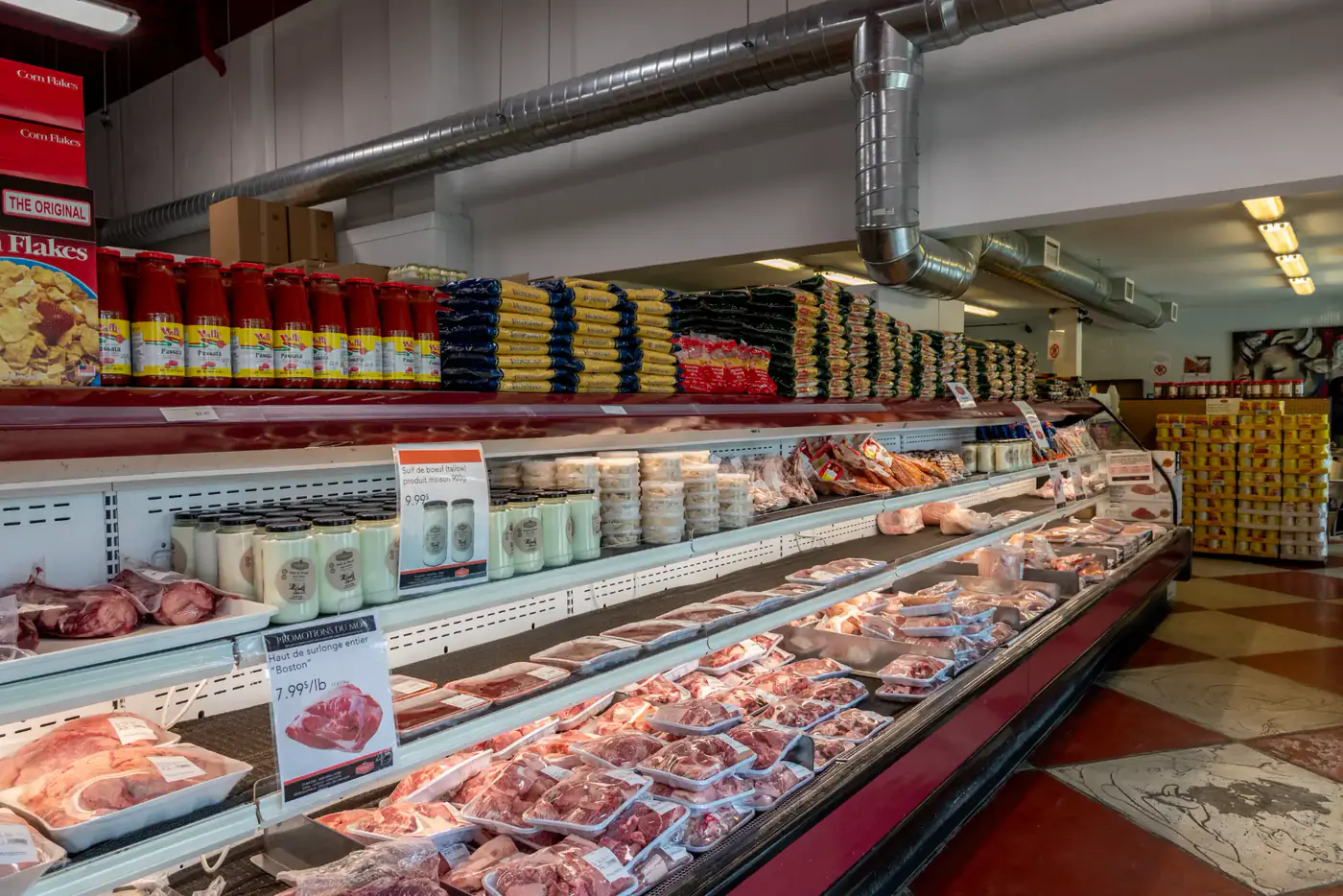 Refrigerated case of packaged meats below grocery shelves at the Longueuil store